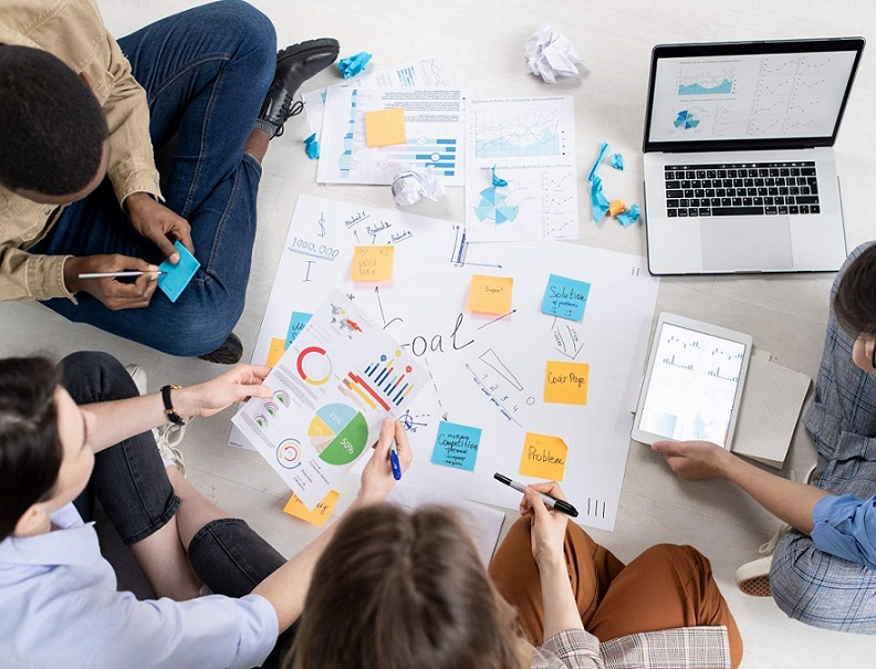 Ein Foto von 4 Personen, die auf dem Boden sitzen und Post-Its sortieren.